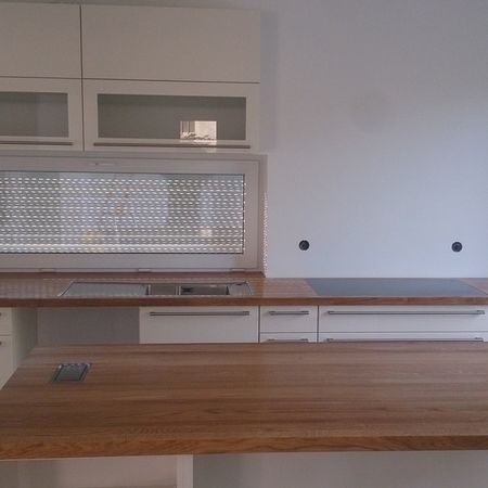 Küchenzeile mit Holzarbeitsplatte und weißem Oberschrank mit Lochblech