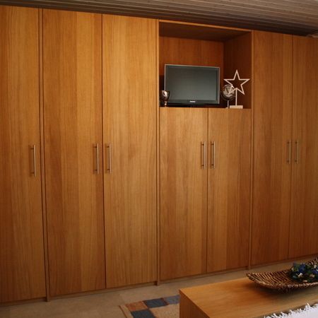 Einbaukleiderschrank aus Holz mit Fernseher im mittleren Fach