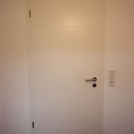 Geschlossene weiße Zimmertür mit Türklinke links