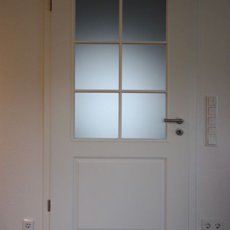 Weiße Tür mit Glasfenstern im oberen Bereich