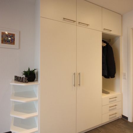 Eingebaute weiße Garderobe mit offenen Regalen und Sitzbank
