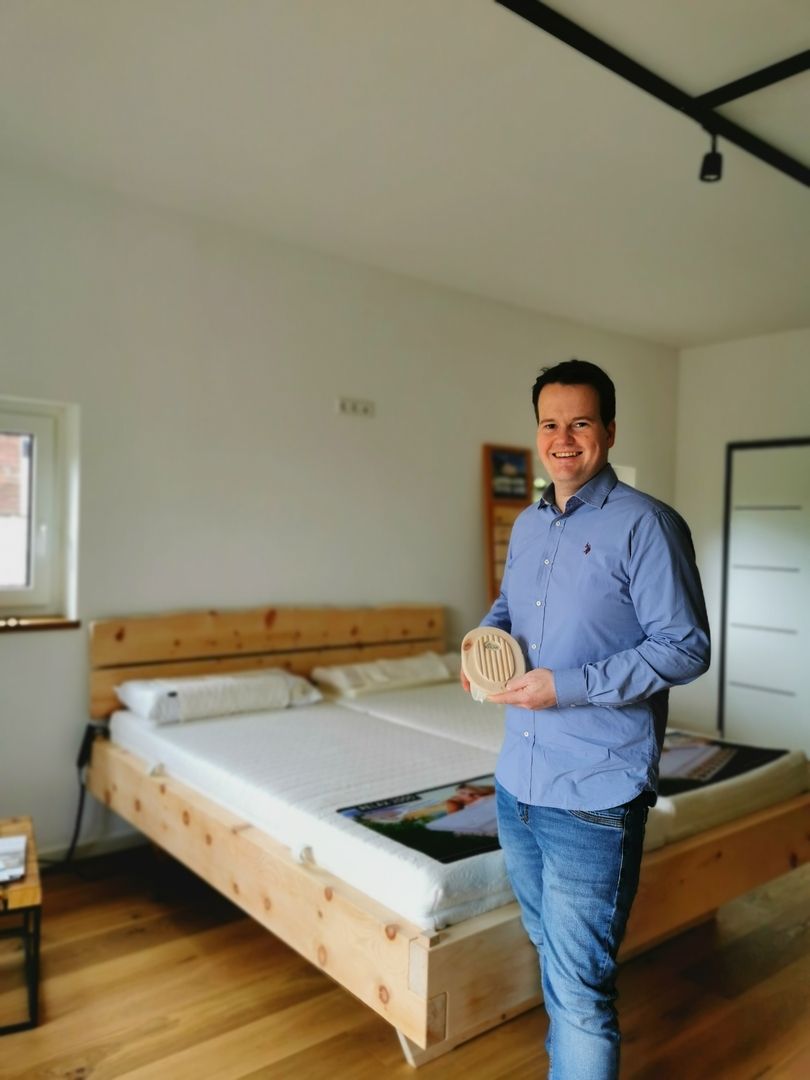 Ein Mann steht vor einem Holzbett