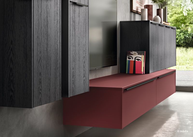 Verschiedene Kommoden und Schränke in dunklem Holz an der Wand